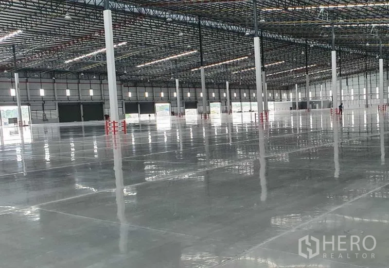 Factory for rent in Si Racha, Chon Buri - Warehouse interior showing multiple loading bays and a wide column grid on glossy concrete.