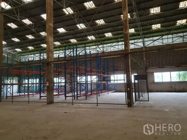 工厂 出租在Samut Prakan - 仓储区设蓝橙色托盘货架，链式围栏分区，屋顶采光充足。