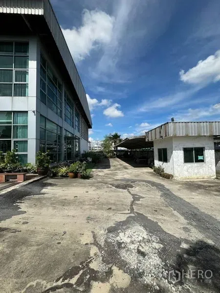 Warehouse for rent in Bang Phli, Samut Prakan - Side view of the warehouse with a security guardhouse and spacious concrete yard for truck access.