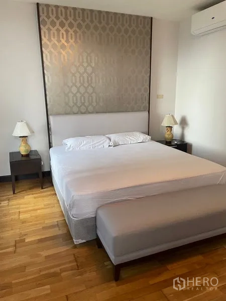 Condominium for rent in Pathum Wan, Bangkok - Master bedroom with king bed, upholstered bench, bedside lamps and feature headboard.