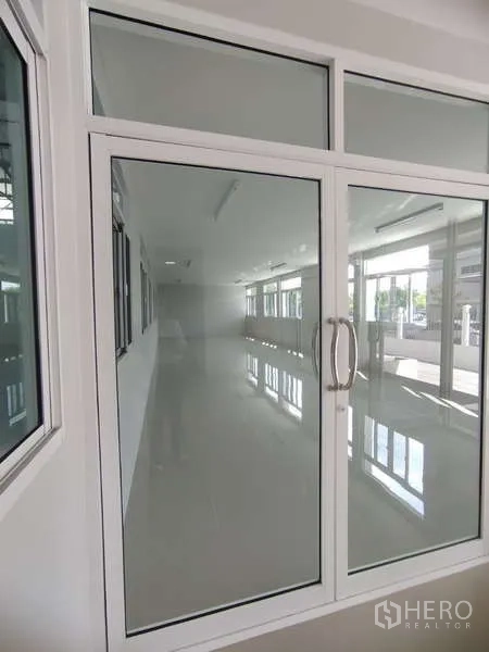 Warehouse for rent in Bang Pakong, Chachoengsao - Bright office area with double glass doors and tiled floor overlooking the warehouse.