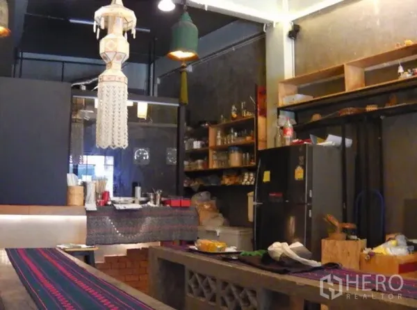 店屋 出租在Watthana, Bangkok - 开放式厨房与置物架区域，配有冰箱、吊灯和混凝土长椅，曼谷店屋内部。