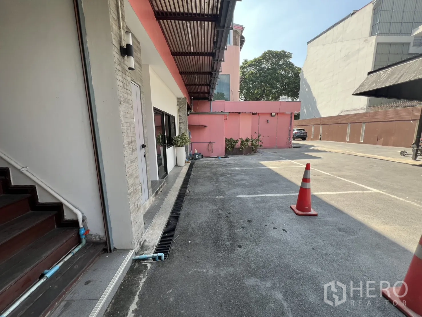 Retail Space for rent - Outdoor parking area beside a low‑rise building with traffic cones.