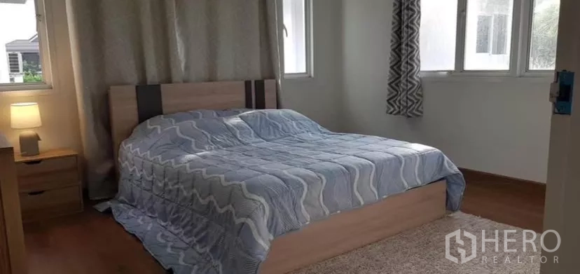 Detached House for rent or sale in Prawet, Bangkok - Sunlit bedroom with double bed, bedside table and multiple windows.
