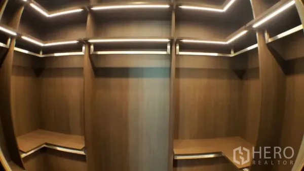 Condominium for rent in Khlong Toei, Bangkok - Built-in walk-in closet with warm wood shelving and LED strip lighting.