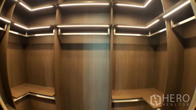 Condominium for rent in Khlong Toei, Bangkok - Built-in walk-in closet with warm wood shelving and LED strip lighting.