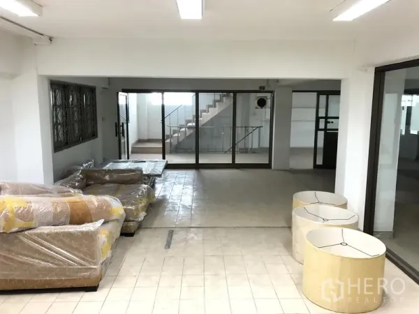办公空间 出租在Huai Khwang, Bangkok - 一层开放空间，瓷砖地面，包裹中的家具、玻璃门与楼梯