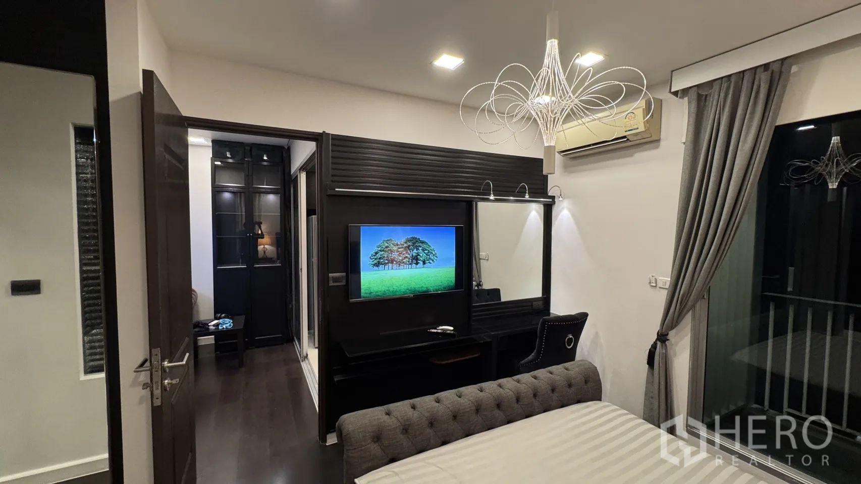 Condominium for rent or sale in Khlong Toei, Bangkok - Bedroom media wall with mounted TV, built-in desk and decorative lighting.