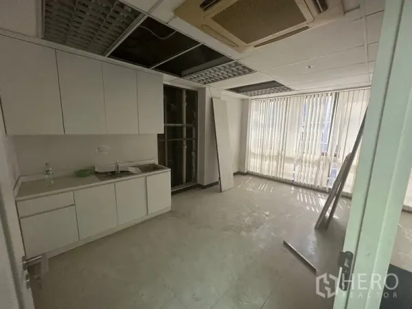 Office Space for rent in Khlong Toei, Bangkok - Office pantry with white cabinets, sink, tiled floor and vertical blinds under a drop ceiling.