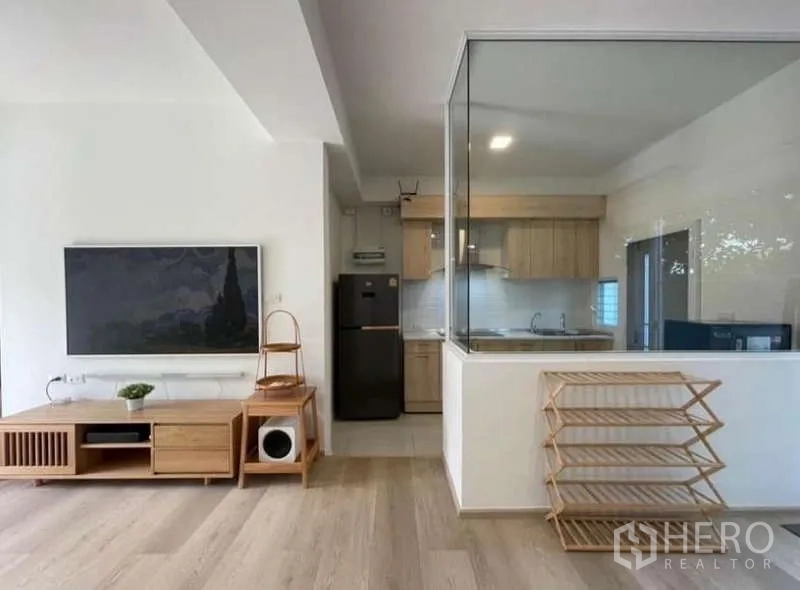 Townhouse for rent in Prawet, Bangkok - TV wall and glass-enclosed kitchen with light wood cabinetry