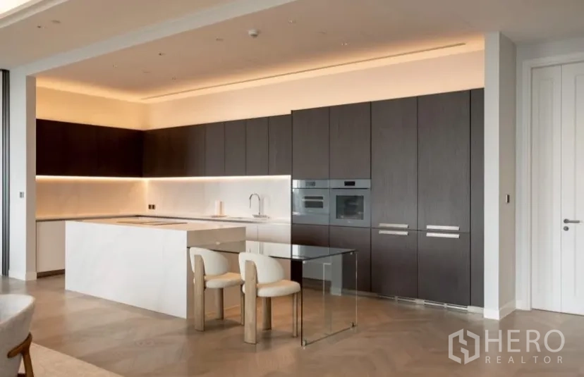 Condominium for rent or sale in Pathum Wan, Bangkok - Modern kitchen wall with full-height storage, built-in ovens and a glass breakfast table.
