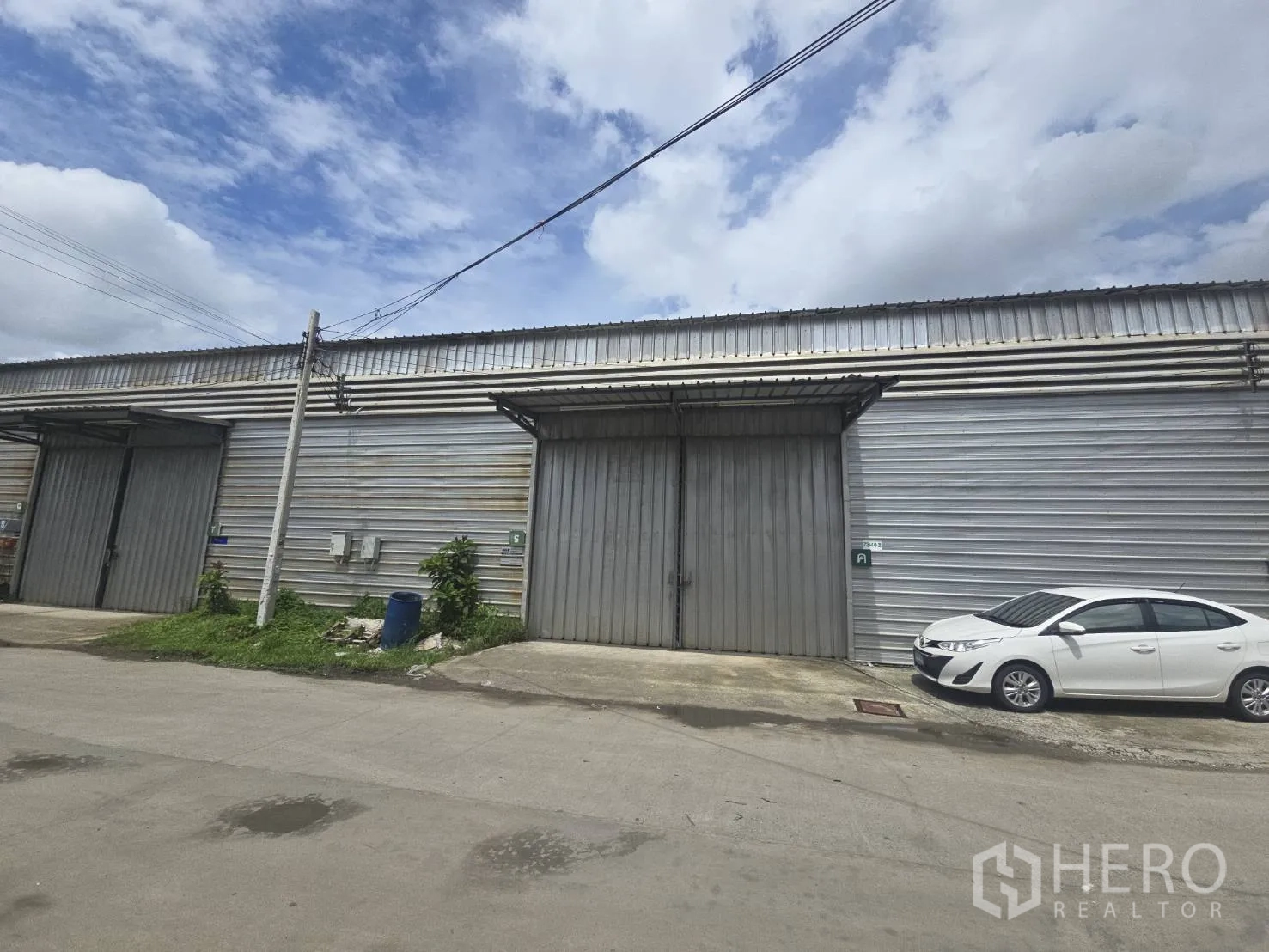 Warehouse for rent in Bang Phli, Samut Prakan - Street view of a metal-clad warehouse in Bang Phli with large sliding doors and roadside parking.