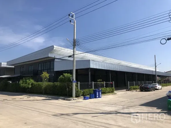 工厂 出租或出售在Bang Bo, Samut Prakan - 转角视角的现代钢结构工厂，临宽阔混凝土道路与停车区。