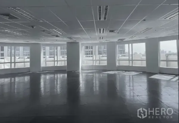 Office Space for rent - Large open-plan office floor with a curved wall of panoramic windows, city views, and drop-ceiling lighting.
