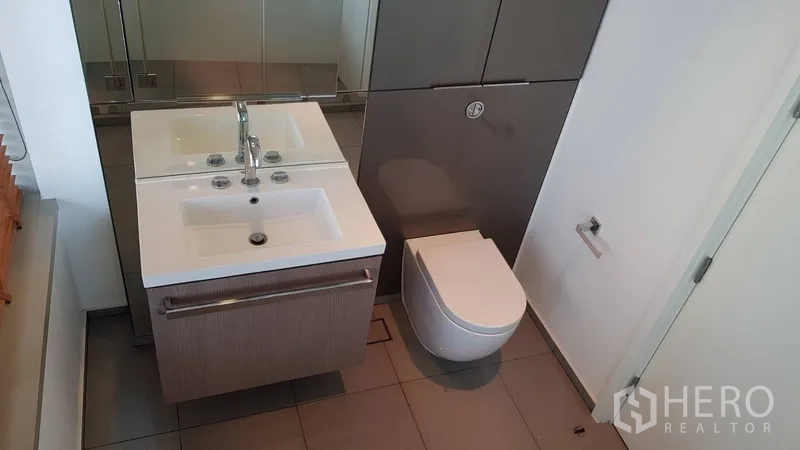 Condominium for rent in Pathum Wan, Bangkok - Contemporary bathroom with double sinks, vanity and wall-hung toilet.
