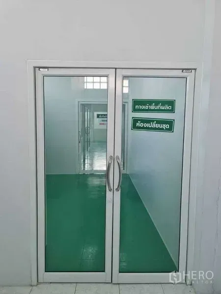 Factory for sale in Bang Pa-in, Phra Nakhon Si Ayutthaya - Glass double doors opening to a production corridor with green epoxy flooring.