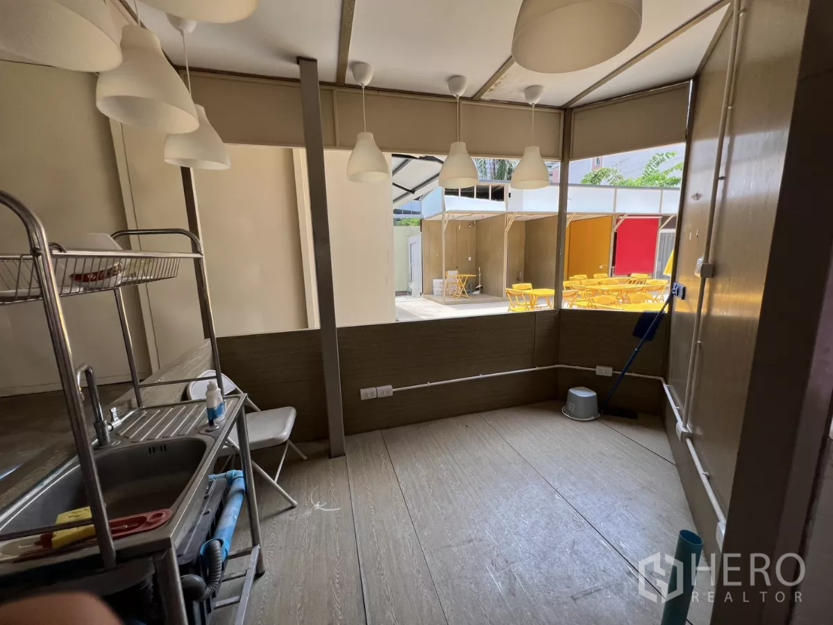 Retail Space for rent in Khlong Toei, Bangkok - Prep corner with multiple pendant lamps, stainless sink and view to a lively courtyard with yellow tables.