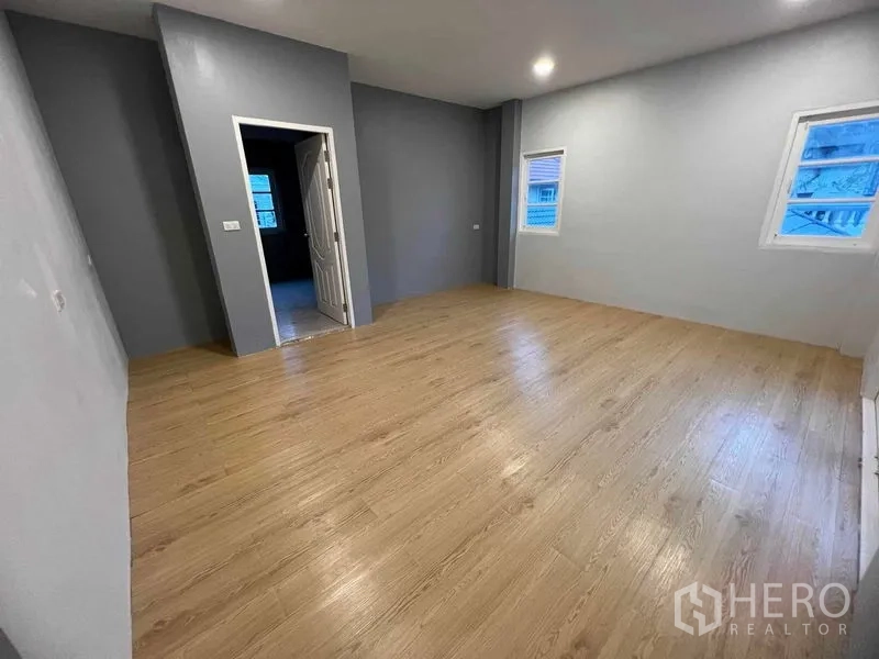 Detached House for sale in Bang Na, Bangkok - Big bedroom with light wood floor, several windows and an en-suite doorway.