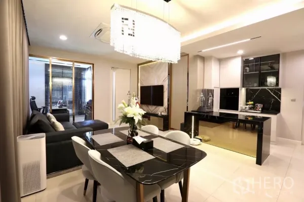 Detached House for rent in Samut Prakan - Open-plan dining and lounge with a black marble dining table and crystal chandelier.