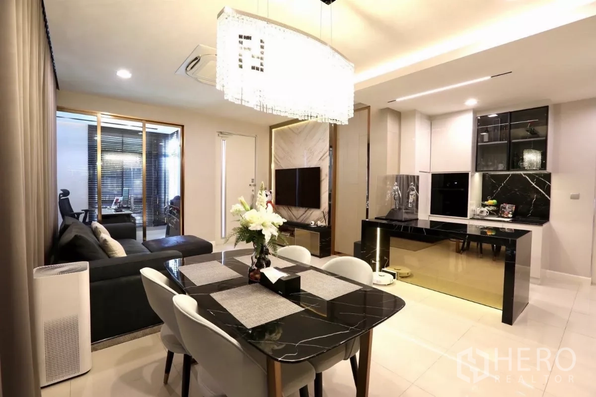 Detached House for rent in Samut Prakan - Open-plan dining and lounge with a black marble dining table and crystal chandelier.