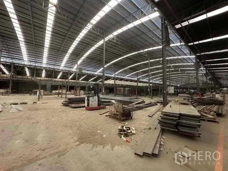 Factory for rent in Pathum Thani - Open production bay with steel columns and equipment across a wide floor space.