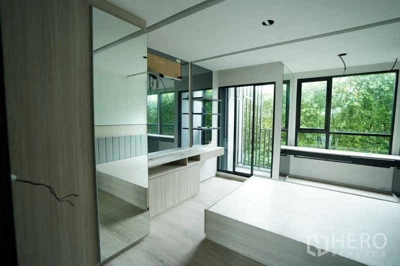 Standalone for rent in Bang Na, Bangkok - Corner room with built-in platform, desk and large windows facing greenery.