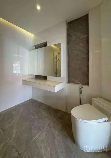 Townhouse for rent or sale in Prawet, Bangkok - Contemporary bathroom with floating vanity, backlit mirror, and toilet.