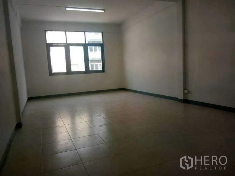Shophouse for rent in Bang Na, Bangkok - Spacious upper-floor room with large window and tiled floor suitable for office use.