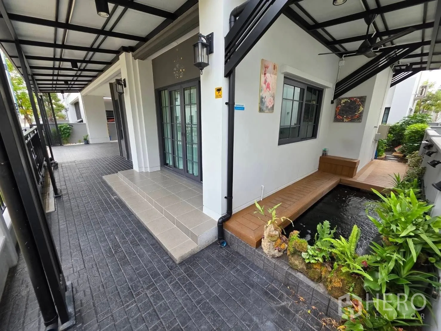Detached House for rent or sale in Bang Phli, Samut Prakan - Shaded terrace with steps and a koi pond bordered by plants.