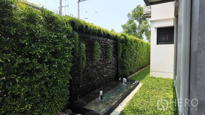 独立式住宅 出租或出售在Bang Na, Bangkok - 侧院设石质景观水墙与茂密树篱，私密而清新。