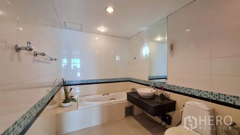 Condominium for rent in Khlong Toei, Bangkok - Bathroom with bathtub, vanity and mosaic tile border.