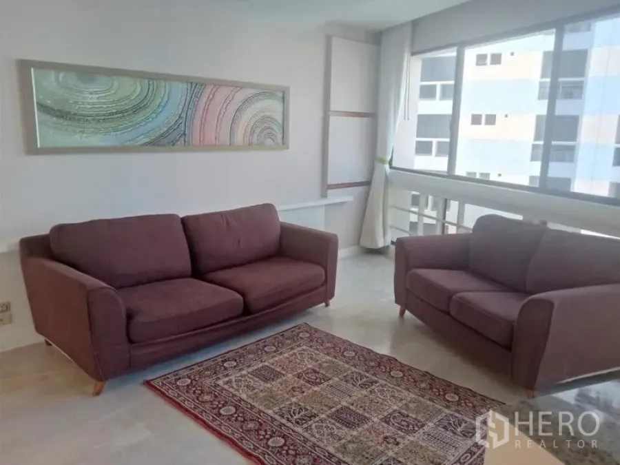 Condominium for rent in Khlong Toei, Bangkok - Bright living room with two plum sofas, large windows and modern art.