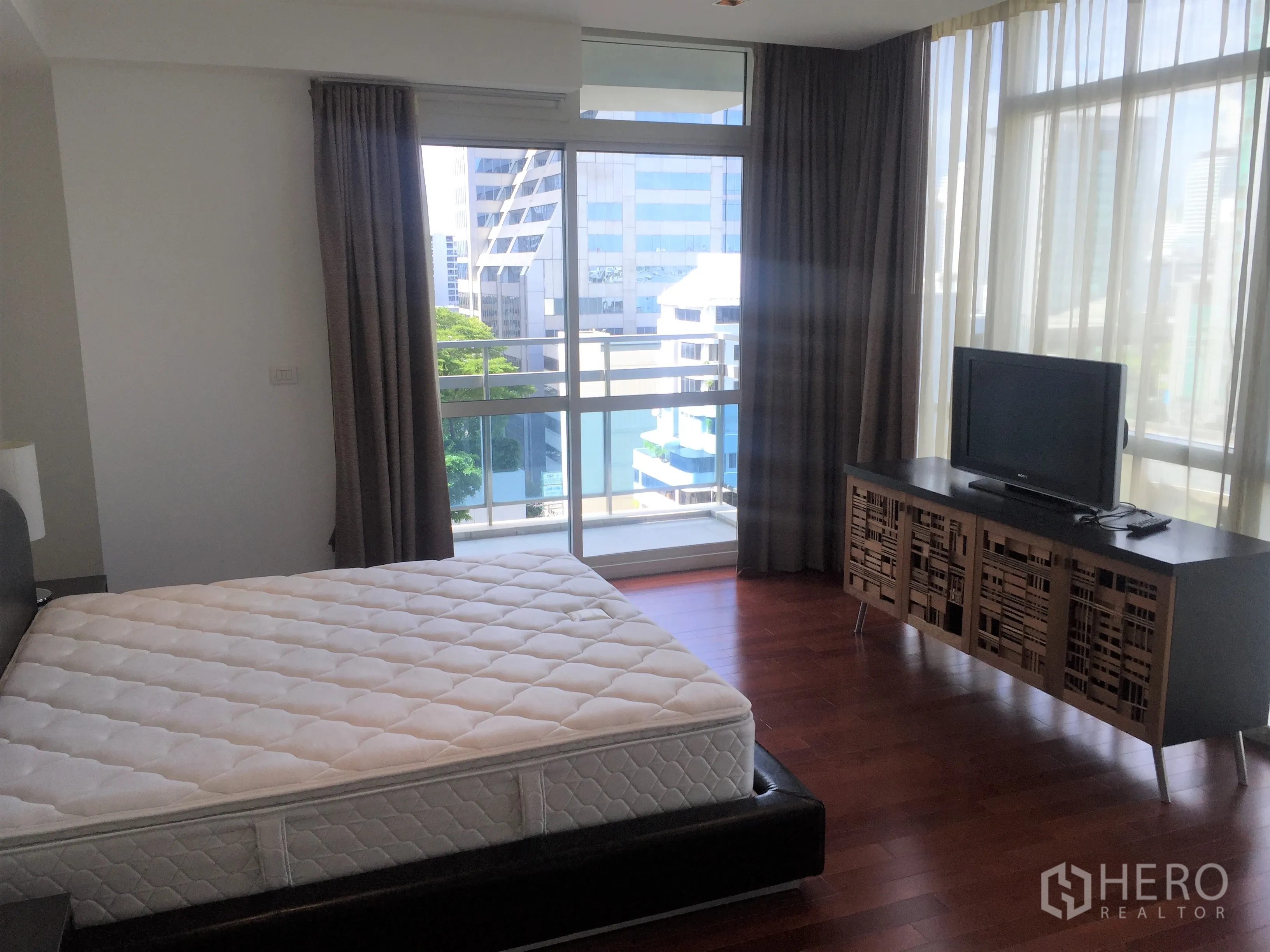 Condominium for rent in Pathum Wan, Bangkok - Sunlit master bedroom with balcony access, city view and floor-to-ceiling windows.