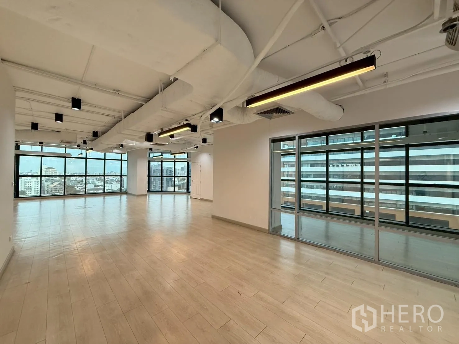 Office Space for rent in Watthana, Bangkok - Corner office area with linear lighting and a glass wall to a smaller room.