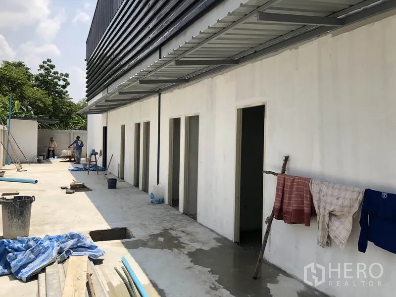 Warehouse for rent in Bang Khen, Nonthaburi - Service area beside the warehouse with multiple restroom doors and a covered walkway.