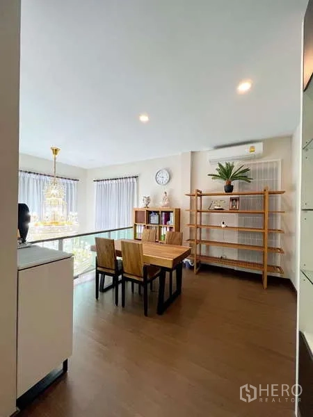 Detached House for sale in Prawet, Bangkok - Open mezzanine study with wooden table, shelving, and a glass balustrade overlooking the chandelier.