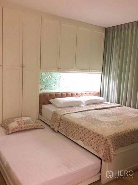 Condominium for rent in Khlong Toei, Bangkok - Bedroom with built-in wardrobes, upholstered headboard, queen bed and pull-out trundle bed with soft green curtains.