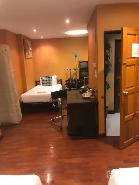 Shophouse for rent in Bang Rak, Bangkok - Spacious twin-bed room with desk, wooden floors and soft ceiling lighting.
