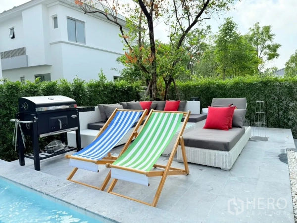 Detached House for rent or sale in Bang Phli, Samut Prakan - Private poolside terrace with BBQ grill, sun loungers and outdoor sofa amid greenery.