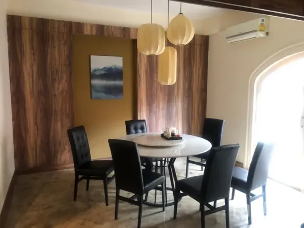 Shophouse for rent in Watthana, Bangkok - Private dining room featuring a round marble table, black chairs, wood feature wall and arched window with AC.