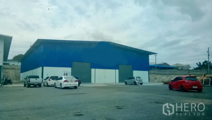 Warehouse for rent in Si Racha, Chon Buri - Blue warehouse exterior with twin roller shutter doors and wide parking and truck access.