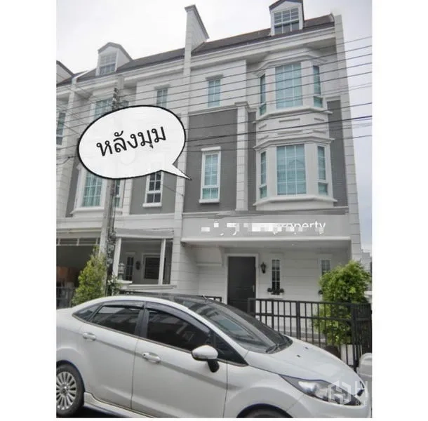 Townhouse for rent in Bang Kapi, Bangkok - Front facade of the townhouse row with tall windows and a driveway behind a black fence.