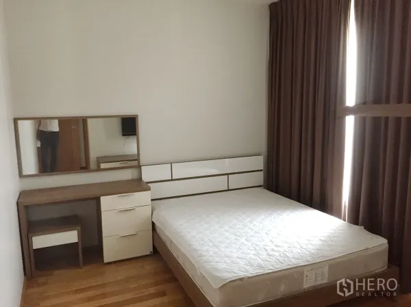 Condominium for rent in Khlong Toei, Bangkok - Bright bedroom with queen-size bed, dressing table, built-in storage, and blackout curtains.
