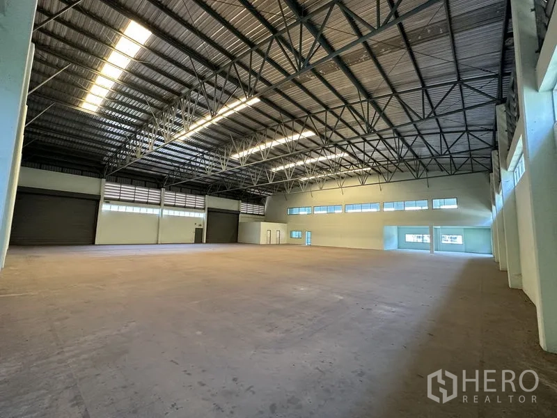 Factory for rent in Chon Buri - Large manufacturing floor featuring multiple loading roller doors and open steel truss ceiling.