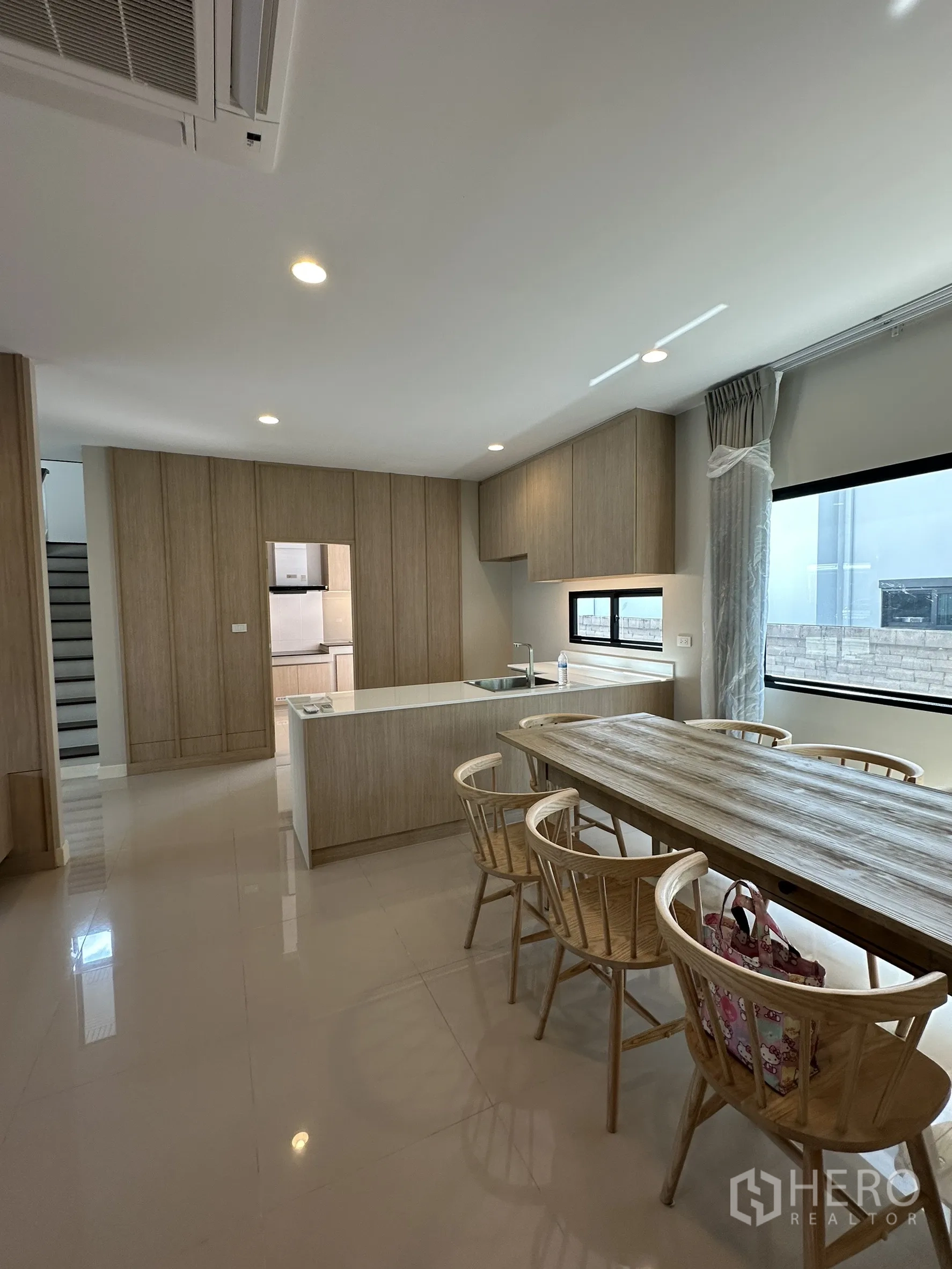 Detached House for sale in Lam Luk Ka, Pathum Thani - Open-plan kitchen and dining with island counter, built-in cabinets and glossy floors.
