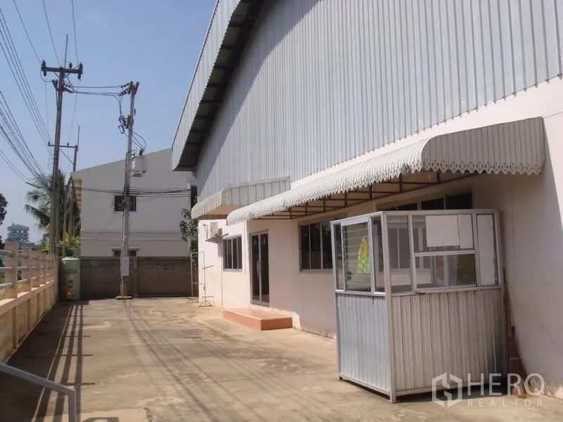 Factory for rent in Lat Lum Kaeo, Pathum Thani - Front setback with awnings and a guard kiosk along the factory facade.