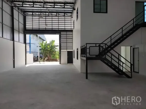 Factory for rent in Lam Luk Ka, Pathum Thani - Open warehouse bay with tall shutter door, side office core and natural ventilation panels.