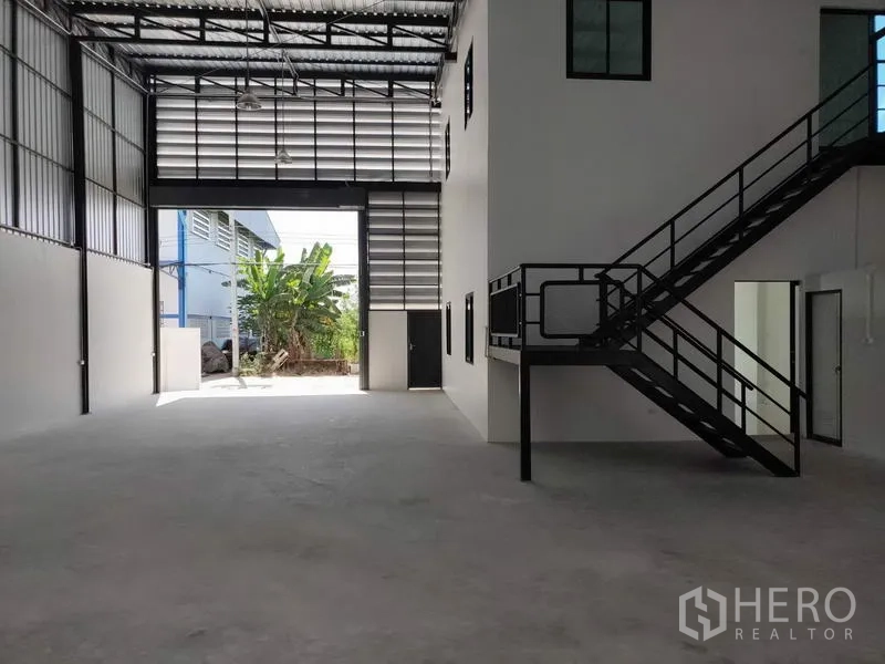 Factory for rent in Lam Luk Ka, Pathum Thani - Open warehouse bay with tall shutter door, side office core and natural ventilation panels.