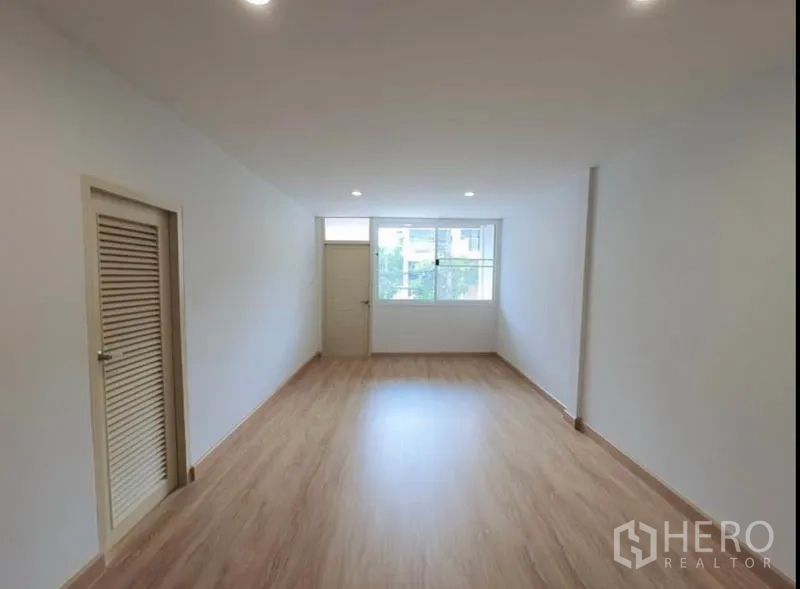 Townhouse for rent in Phaya Thai, Bangkok - Large bedroom with window, wood flooring and access to an adjoining room.