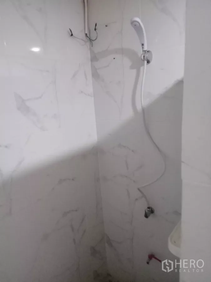 Detached House for rent in Phaya Thai, Bangkok - Shower corner with white marble-look tiles and water heater.